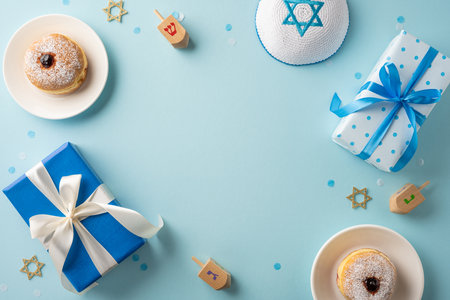 A festive Hanukkah scene featuring gifts wrapped in blue and white with dreidels and donuts on a light blue backgroundの写真素材