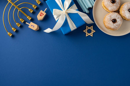 A Hanukkah celebration setup featuring a menorah, dreidels, gifts, and traditional donuts on a blue background. The elements evoke the festive and joyful spirit of the Hanukkah holidayの写真素材