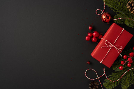Red Christmas present surrounded by festive decorations and ornaments on a dark background creating a cozy holiday atmosphereの写真素材