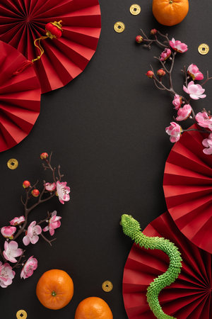 An elegant vertical Chinese New Year celebration scene featuring red fans, oranges, cherry blossoms, and decorative gold coins symbolizing prosperityの写真素材