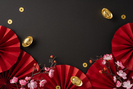 Elegant Chinese New Year themed background with red paper fans, gold coins, and blooming peach blossoms on a dark backdropの写真素材