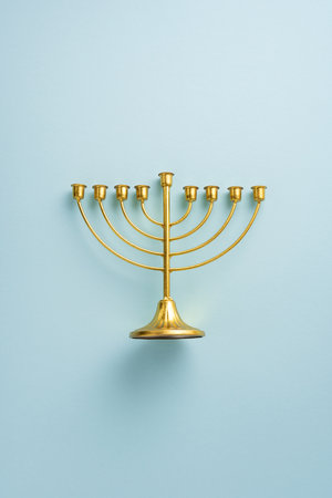 Elegant vertical gold menorah with eight branches displayed on a soft light background, symbolizing the festive spirit of Hanukkahの写真素材