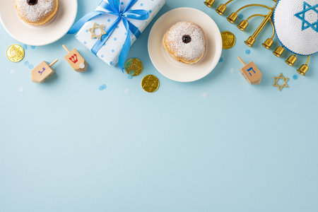Celebrate Hanukkah with traditional elements including donuts, dreidels, and a menorah on a light blue backdrop, evoking joy and traditionの写真素材