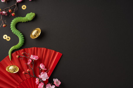 Elegant setup showcasing Chinese new year with vibrant red fan, gold coins, green snake, and cherry blossoms symbolizing prosperity and good fortuneの写真素材
