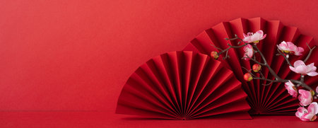 Red paper fans and cherry blossoms on a vibrant background symbolize Chinese new year 2025 traditions. This festive arrangement is perfect for cultural celebrations and invitationsの写真素材