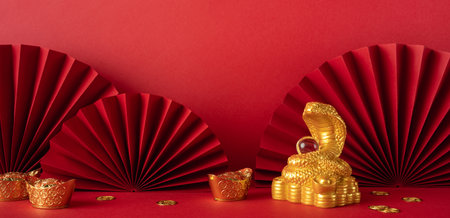 An elegant arrangement celebrating Chinese New Year 2025, featuring gold decorations, a snake figure, and red paper fans. It traditional reflects Asian cultural elements and festive symbolismの写真素材
