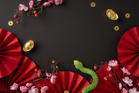 Celebrate the Chinese New Year with elegant decorations featuring red fans, cherry blossoms, gold coins, and a symbolic green snake, set against a dark background for a festive atmosphereの写真素材