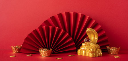 Elegant gold snake symbolizing Chinese New Year 2025 with red fans and gold accents, perfect for festive decorations and greeting cardsの写真素材