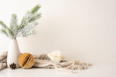 Minimalist side view Scandinavian Christmas decor featuring frosted pine branches in a vase, cozy knit blanket and geometric ornaments conveying a sense of warmth and winter eleganceの写真素材