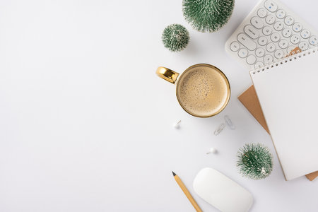 A top view of a winter-themed workspace featuring a coffee cup, keyboard, notebook, and decorative plants. Ideal for creative professionals and winter office inspirationの写真素材