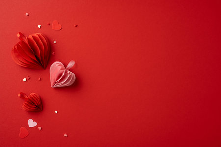 A collection of red and pink paper hearts arranged on a red background, symbolizing love and romance, perfect for Valentine's Day themesの写真素材