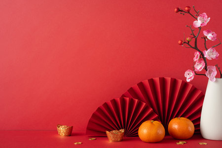 Red-themed setting for Chinese New Year 2025 featuring tangerines, cherry blossoms, and traditional decorations invoking a festive cultural atmosphereの写真素材