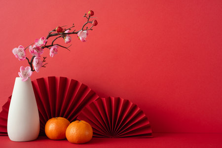 Celebrate Chinese New Year 2025 with a festive arrangement of tangerines, cherry blossoms, and red paper fans, symbolizing happiness and prosperity in traditional Asian cultureの写真素材