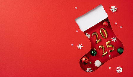Festive 2025 scene featuring a Christmas sock cutout with ornaments and golden numbers on a red backdropの写真素材