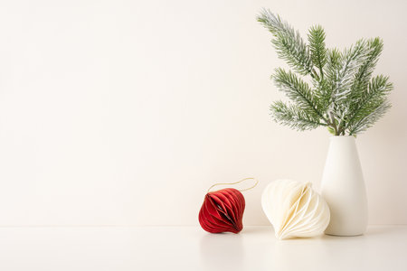 Elegant side view Scandinavian Christmas setup with white pottery vase, pine branches, and paper ornaments in a minimalist style. Perfect for holiday decor inspiration and seasonal aestheticsの写真素材