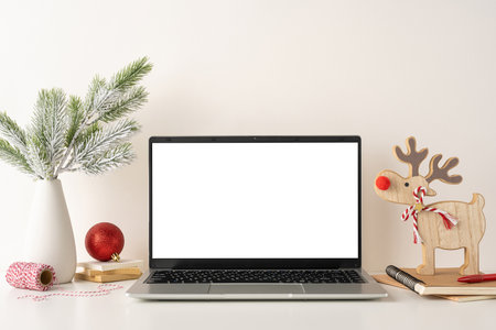 A side view of simple, scandinavian-style workspace with a laptop and festive decorations, including a reindeer figurine and pine branches. The scene creates a cozy and holiday-friendly atmosphereの写真素材