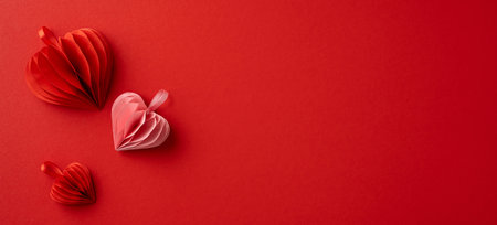 Three paper hearts on a red backdrop representing love, romance, and Valentine's Day. The vibrant scene conveys feelings of warmth and affectionの写真素材