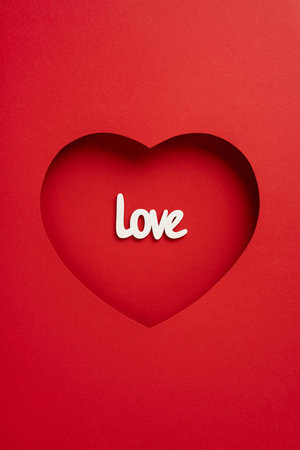 A vertical heart cutout in red paper with the word 'love' inside, symbolizing romance and affection. Ideal for Valentine's Day greetings and romantic expressionsの写真素材