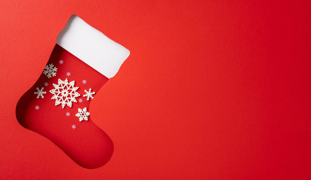 Creative top view Christmas stocking with snowflakes ornaments on a vibrant red background conveying festive holiday spiritの写真素材