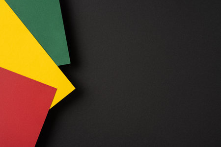 Brightly colored red, yellow, and green paper sheets arranged against a dark background forming a vibrant contrast, ideal for designs expressing creativity, cultural identityの写真素材