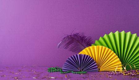 Bright and festive Mardi Gras side view decorations with beads, feathers, and paper fans on a purple backgroundの写真素材