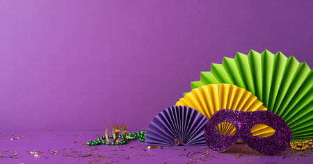 Side view colorful Mardi Gras accessories including a glittery purple mask, festive beads, and paper rosettes arranged on a bold purple background, capturing the celebratory essence of the festivalの写真素材