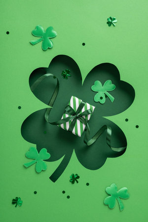 Green vertical shamrock cutout with decorative elements, featuring a small striped gift box displayedの写真素材