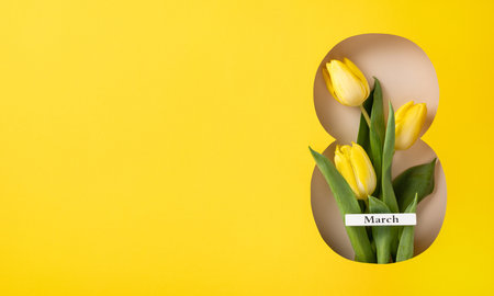Yellow tulips arranged in a shaped cutout against a vibrant yellow background, symbolizing March and International Women's Dayの写真素材