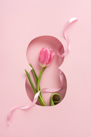 Vibrant vertical pink tulip with its leaves placed inside an eight-shaped cutout and decorative ribbonの写真素材
