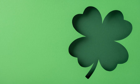 A four-leaf clover cutout silhouette on a green background symbolizing luck and prosperityの写真素材
