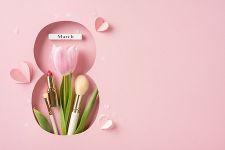 A creative flat lay design with tulips, lipstick, brush, and pink decorations symbolizing femininity and celebrationの写真素材