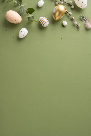 A vertical festive Easter arrangement featuring decorative eggs, greenery, and feathers on a green backdropの写真素材