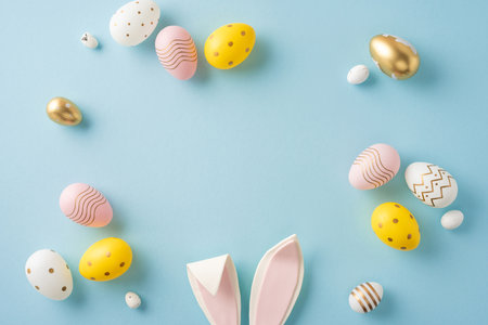 Easter-themed arrangement of colorful decorative eggs and bunny ears displayed on a pastel surfaceの写真素材