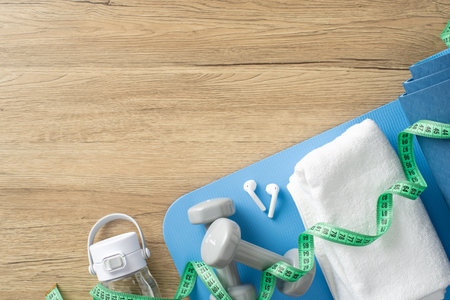 Fitness items including dumbbells, towel, water bottle, and tape measure arranged for home workoutの写真素材
