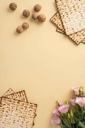 Decorative vertical Passover arrangement featuring matzah bread, scattered walnuts, and delicate pink flowers on a neutral beige backgroundの写真素材
