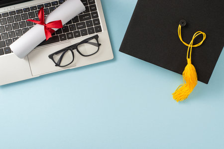 Graduation cap, diploma, and glasses on a laptop symbolize academic achievements and celebrationsの写真素材
