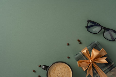 Scene featuring a present wrapped in gold ribbon, alongside coffee and glasses on green backdropの写真素材