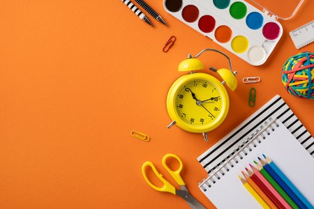 School supplies including pencils, supplies, and colorful items displayed creatively on a vibrant orange background creating a cheerful back-to-school atmosphereの写真素材