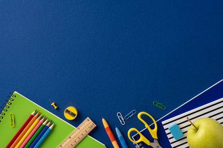 School supplies arranged on a blue background featuring colorful pencils, notebooks, and...