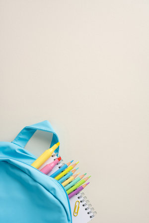 School vertical minimal supplies with colorful pencils and notebook arranged around a backpack for learningの写真素材