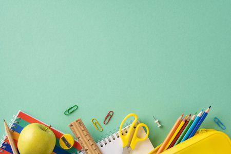 Organized school supplies on a green background, including pencils, notebooks, scissors, and a ruler, symbolizing education and creativityの写真素材