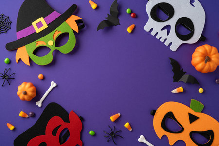 Vibrant Halloween-themed flat lay featuring colorful masks, candy, pumpkins, and festive decorations.の写真素材