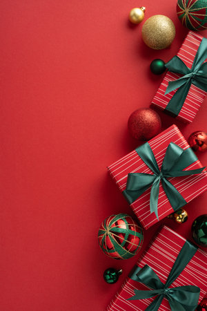Elegant Christmas gifts wrapped with black bows surrounded by festive ornaments on a red backgroundの写真素材