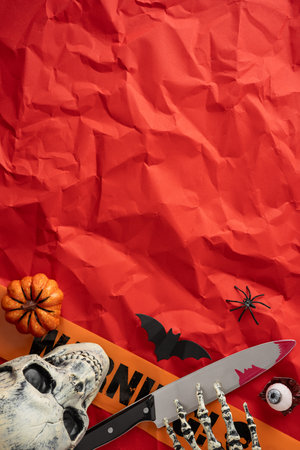Spooky vertical Halloween themed arrangement with a skull, a knife, decorations, and a vibrant backgroundの写真素材