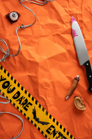 Creepy vertical Halloween decor with knife, props, and warning tape creating a sinister moodの写真素材