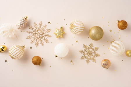 Golden and white decorative Christmas ornaments arranged on a soft beige background, evoking holiday elegance and celebrationの写真素材