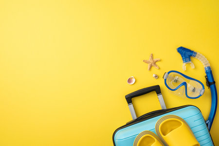 Bright image of vacation essentials, featuring a suitcase, snorkeling gear, and shells, set against a vibrant yellow backdrop evoking feelings of relaxation, fun, and tropical holidaysの写真素材