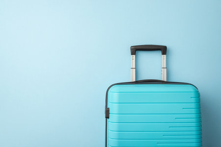A blue hard-shell suitcase positioned in front of a light blue backdrop, evoking travel plansの写真素材