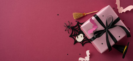 Halloween-themed pink gift box with decorations including bats, a broomstick, spider web, and stars