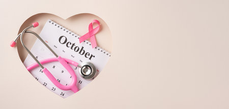 Pink ribbon and stethoscope placed on October calendar symbolizing breast cancer awarenessの写真素材